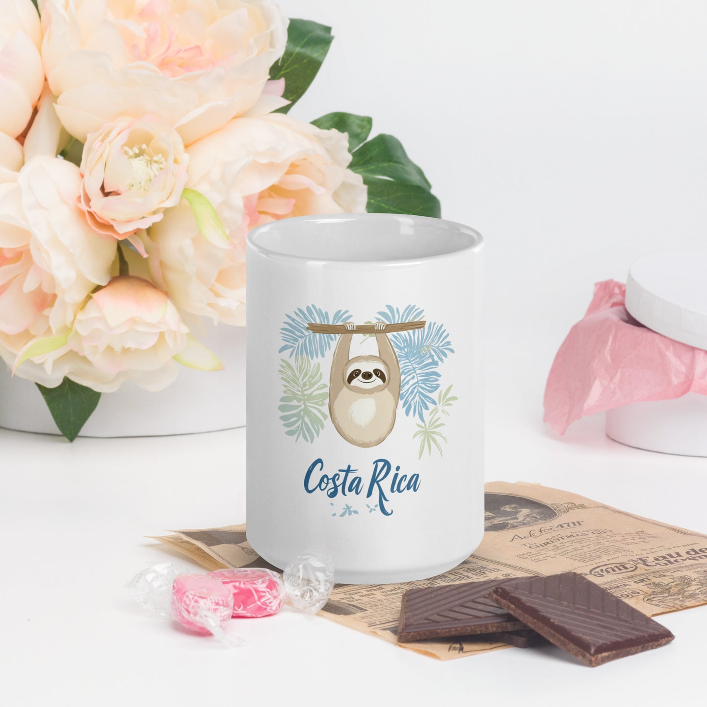 Decorative coffee mug featuring a cute beige sloth hanging from a branch surrounded by light blue and mint green palm leaves, with 'Costa Rica' written in flowing blue script below